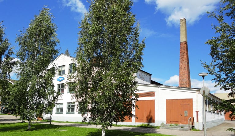 Nuutajärvi glasbruk: vit fabriksbyggnad med skylten Nuutajärvi 1793, en tegelskorsten och björkar