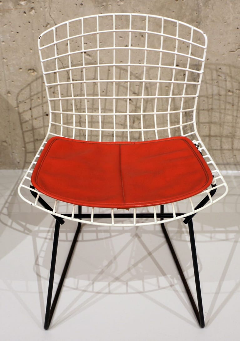 Barnstol av Harry Bertoia med vitt trådnät, svart underrede och röd sittdyna