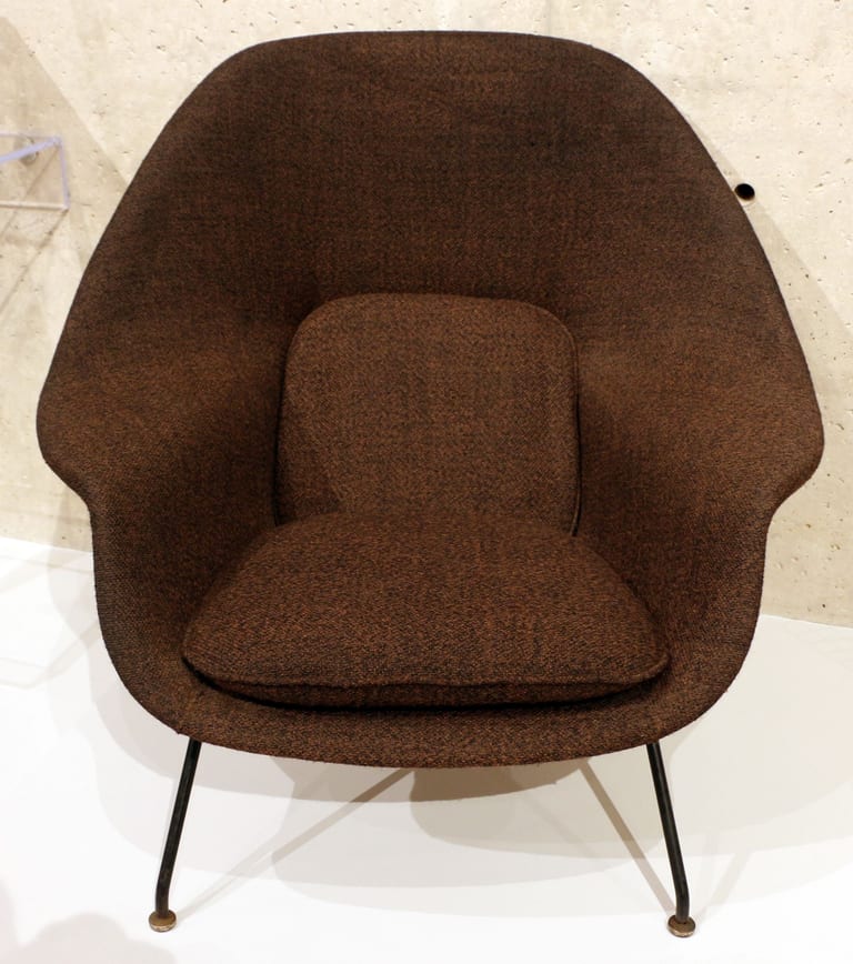 Eero Saarinens Womb Chair, modell 70, klädd i brunt tyg med lös sitt- och ryggdyna på smala svarta stålben