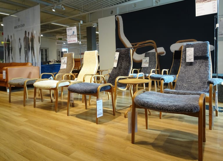 Flera Lamino-fåtöljer med pallar, klädda i grått och vitt fårskinn, uppställda i en möbelbutik