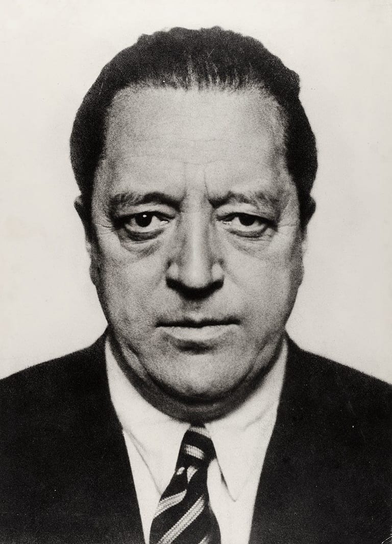 Porträtt av Ludwig Mies van der Rohe i mörk kavaj och randig slips, svartvitt fotografi