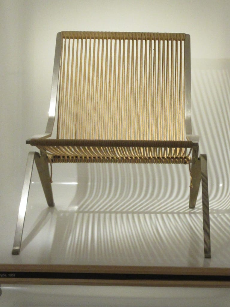 Poul Kjærholms stolsprototyp från 1951 med ram i plattstål och sits och rygg av flaglina, i en monter på Designmuseum Danmark