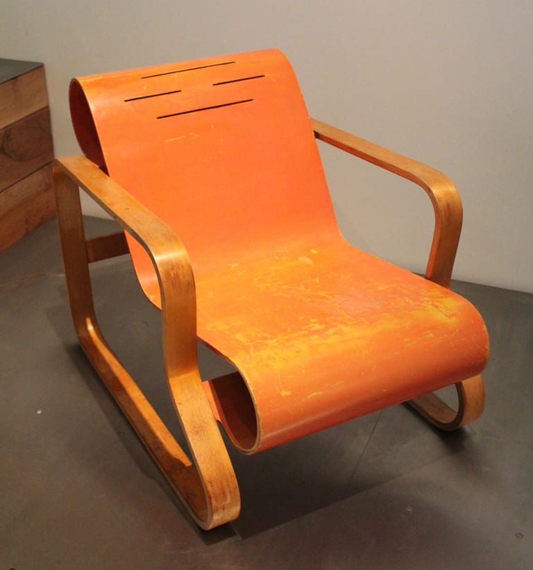 Paimio-stolen av Alvar Aalto med sits och rygg i orangeröd målad plywood med snitt i ryggen och ram i ljus böjd björk